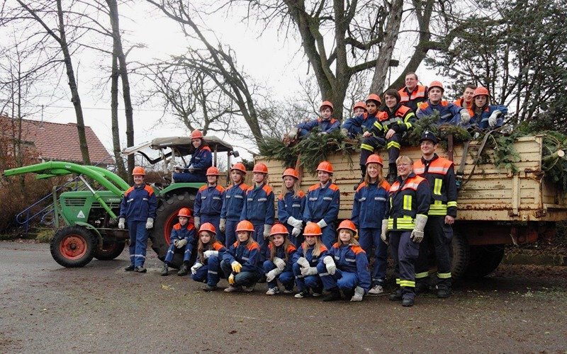 Die erfolgreiche Sammlertruppe vor dem Traktor und Anhänger voller Weihnachtsbäume